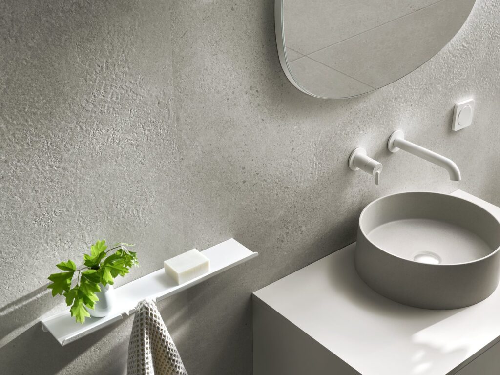 Minimalistička kupaonica s modernim umivaonikom, zidnom slavinom i teksturiranim mineralnim zidnim oblogama u svijetlosivom tonu, dekor Masi Grey